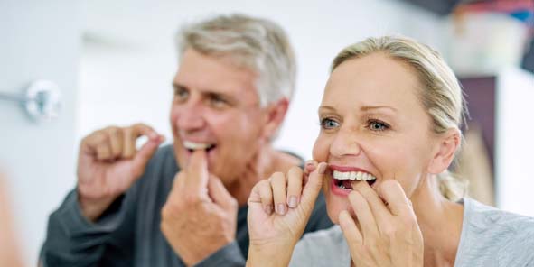 Paar benutzt Zahnseide, nachdem es implantate trotz Zahnfleischentzündung erhalten hat.