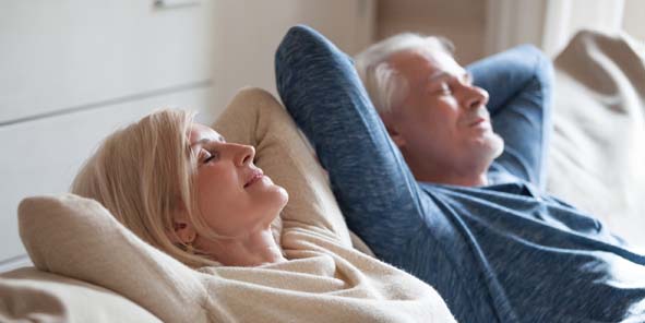 Älteres Paar ruht auf Sofa, um nach der Implantation Schmerzen zu vermeiden.